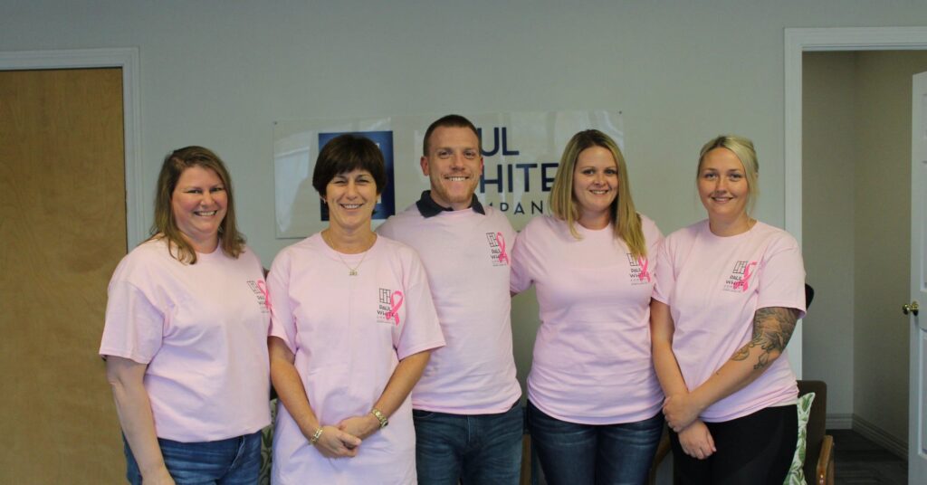 A group of Paul White Company employees pose for a photo while wearing Breast Cancer Awareness Month t-shirts