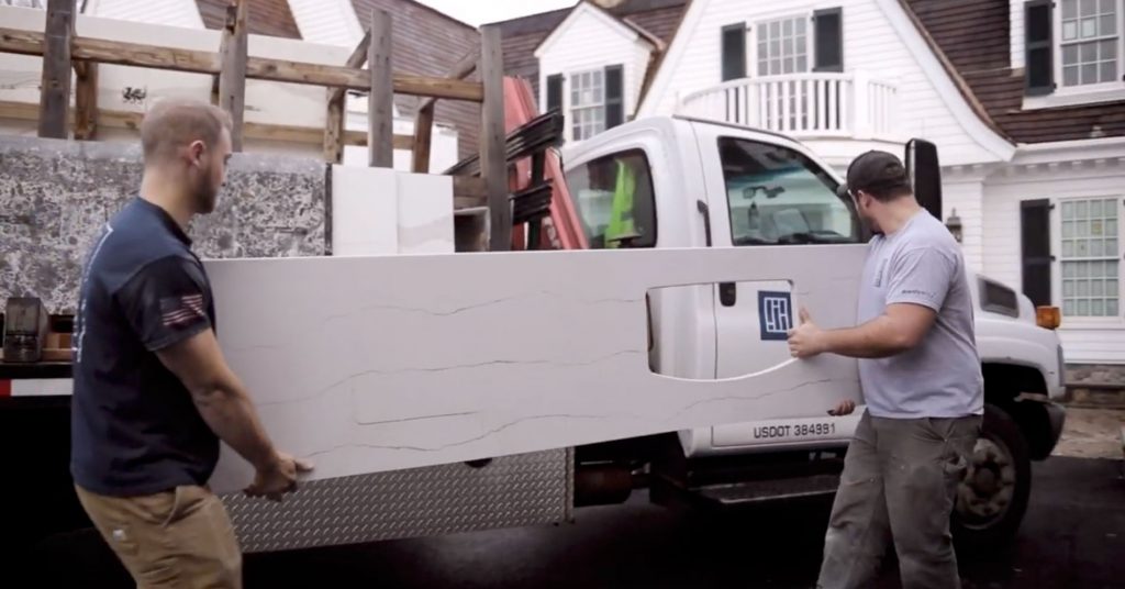 Two Paul White Company team members unloading a custom cut stone from the Portland Maine stone shop before a residential installation