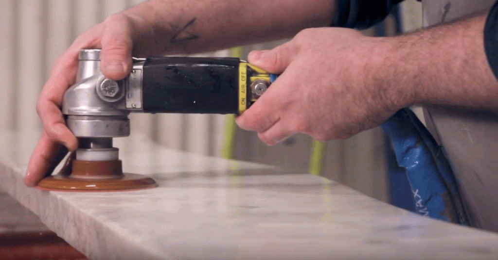 A Paul White Company employees uses an industrial smoother on a marble slab